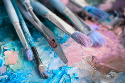 An array of paint brushes displayed on a colorful background.