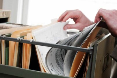 a person rifling through a drawer in a filing cabinet