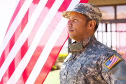 man dressed in military uniform standing before the U.S. flag