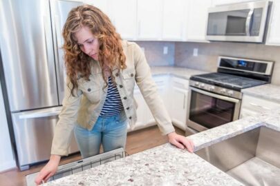 Woman examining granite counter top inside an apartment.