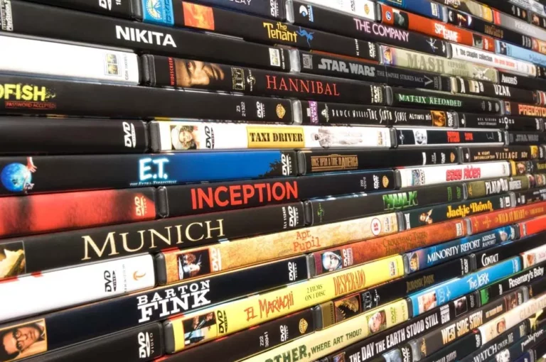 A large stack of DVDs on a storage shelf.