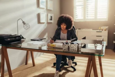 Young woman sits and well-organized desk and writes.