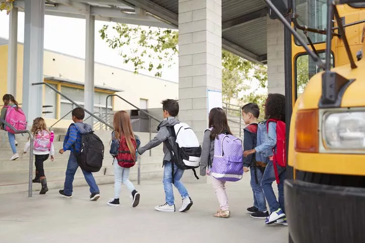 Children exiting a bus and walking to an elementary school.