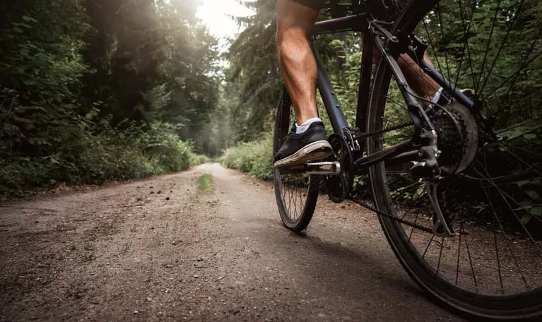 A man biking on a dirt trail in the woods.