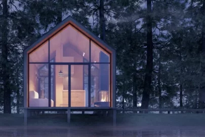 A small home in the woods with a lot of windows.