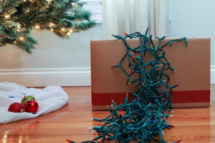 a cardboard box sitting on the floor with holiday lights spilling out of it