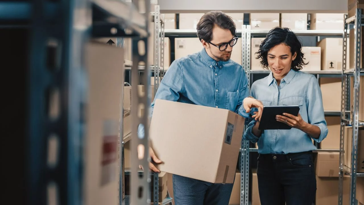 A man and women reviewing inventory, surrounded by boxes