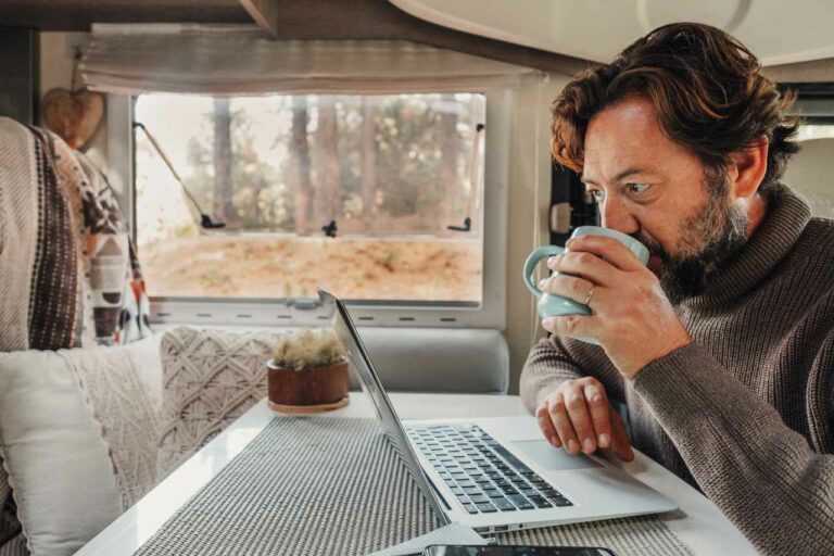 A man works on his laptop while sitting in his camper van