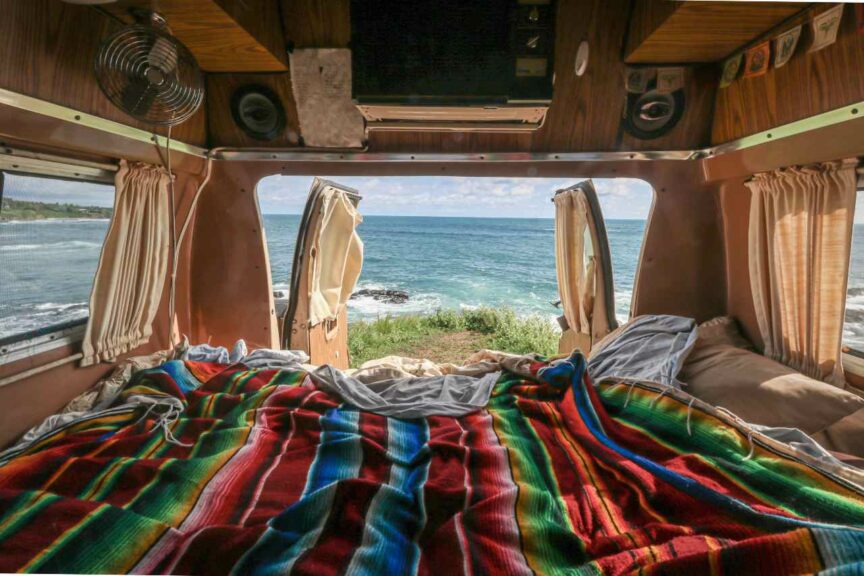 View of the ocean from the back of a van with a colorful bedspread