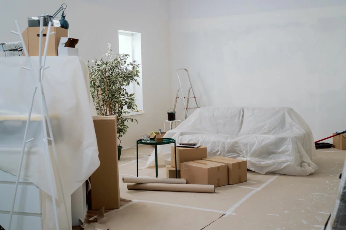 A room prepped for painting with paper on the floor and furniture covered.