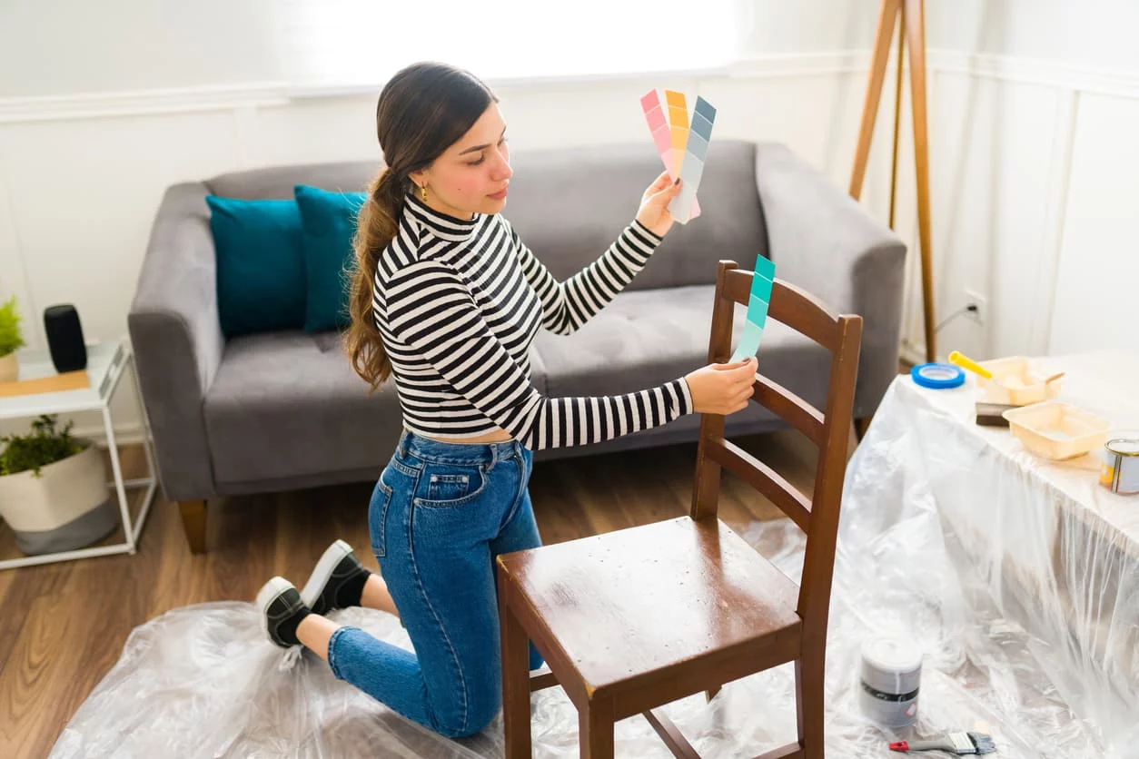 Young woman deciding on paint color for furniture restoration.