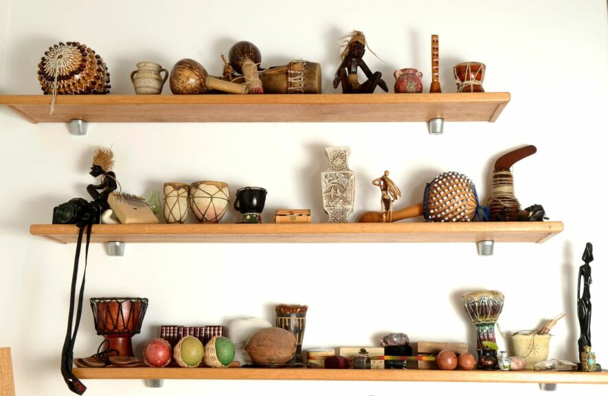 View of three wooden shelves displaying figurines and collectibles.