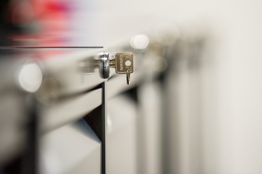 A silver key resting in the lock of a filing cabinet. 