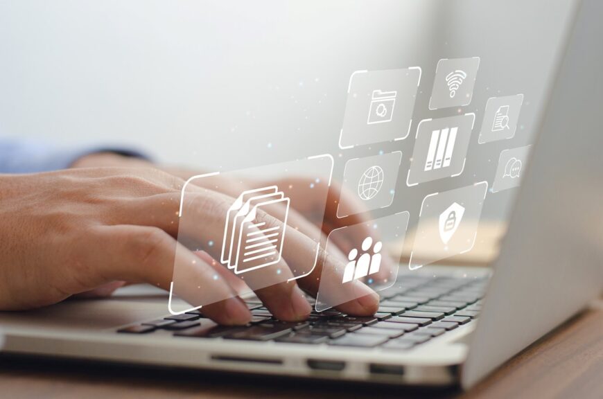 Hands typing on a laptop keyboard with various icons floating around. 