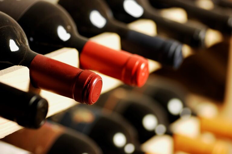 Bottles of red wine stored sideways on a wooden wine rack. (