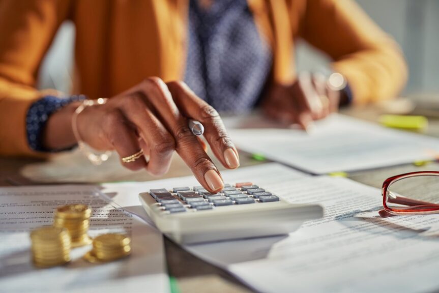 A woman crunches numbers on a calculator as she works on her tax return. 