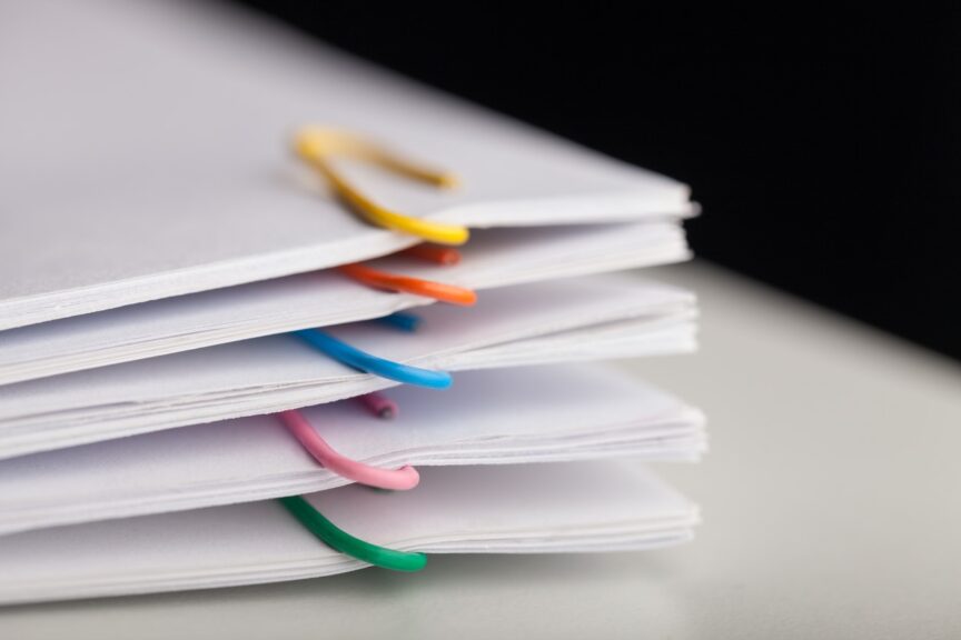 A stack of papers with different-colored paperclips attached. 