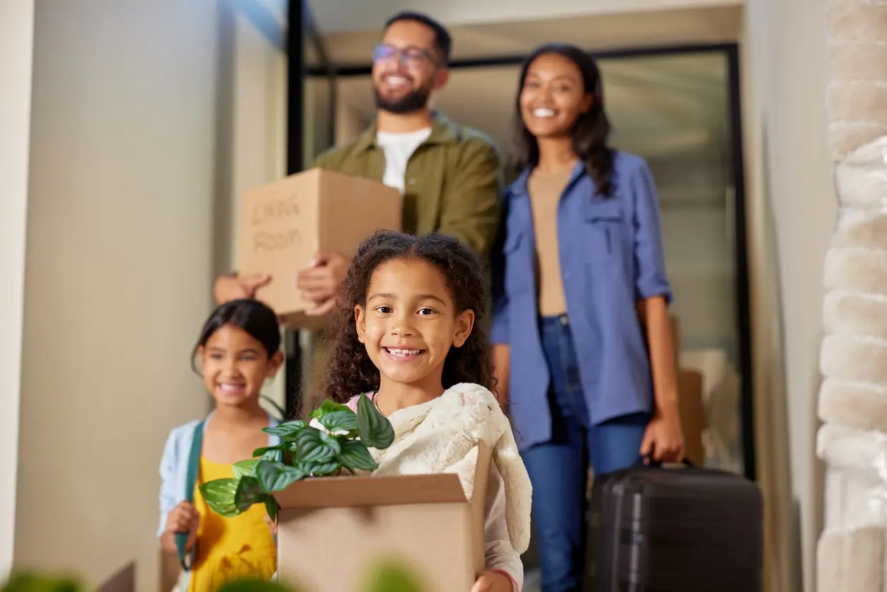 A happy family moves boxes of belongings out of their home. 