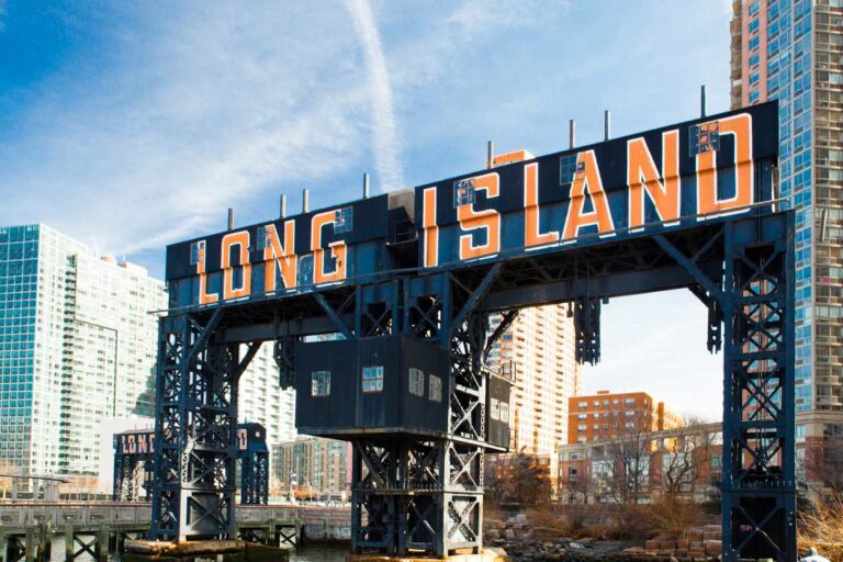 A large sign reading “Long Island City” in orange letters on the riverfront.