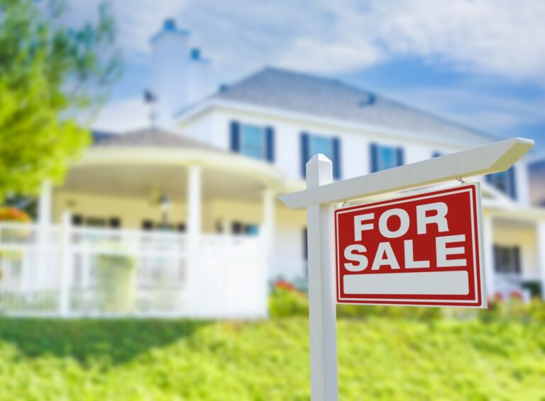 A modern home with a “For Sale” sign in the front yard.