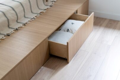 A bed with an open drawer with bedding and pillows inside.