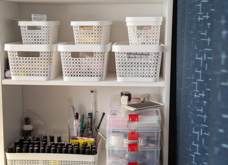 A small shelf neatly arranged with white and clear containers and a variety of nail polishes and manicure supplies.